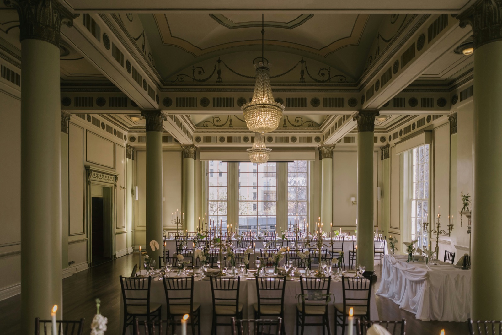 An elegant ballroom with long banquet tables and chandeliers