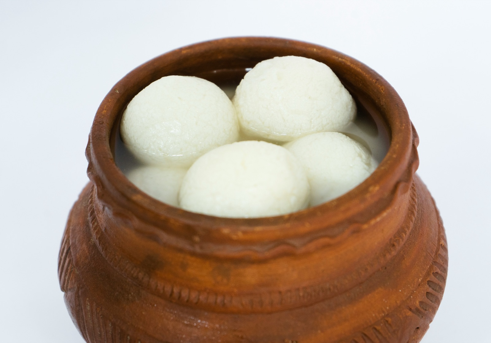 A clay bowl filled with white rosogolla sweets