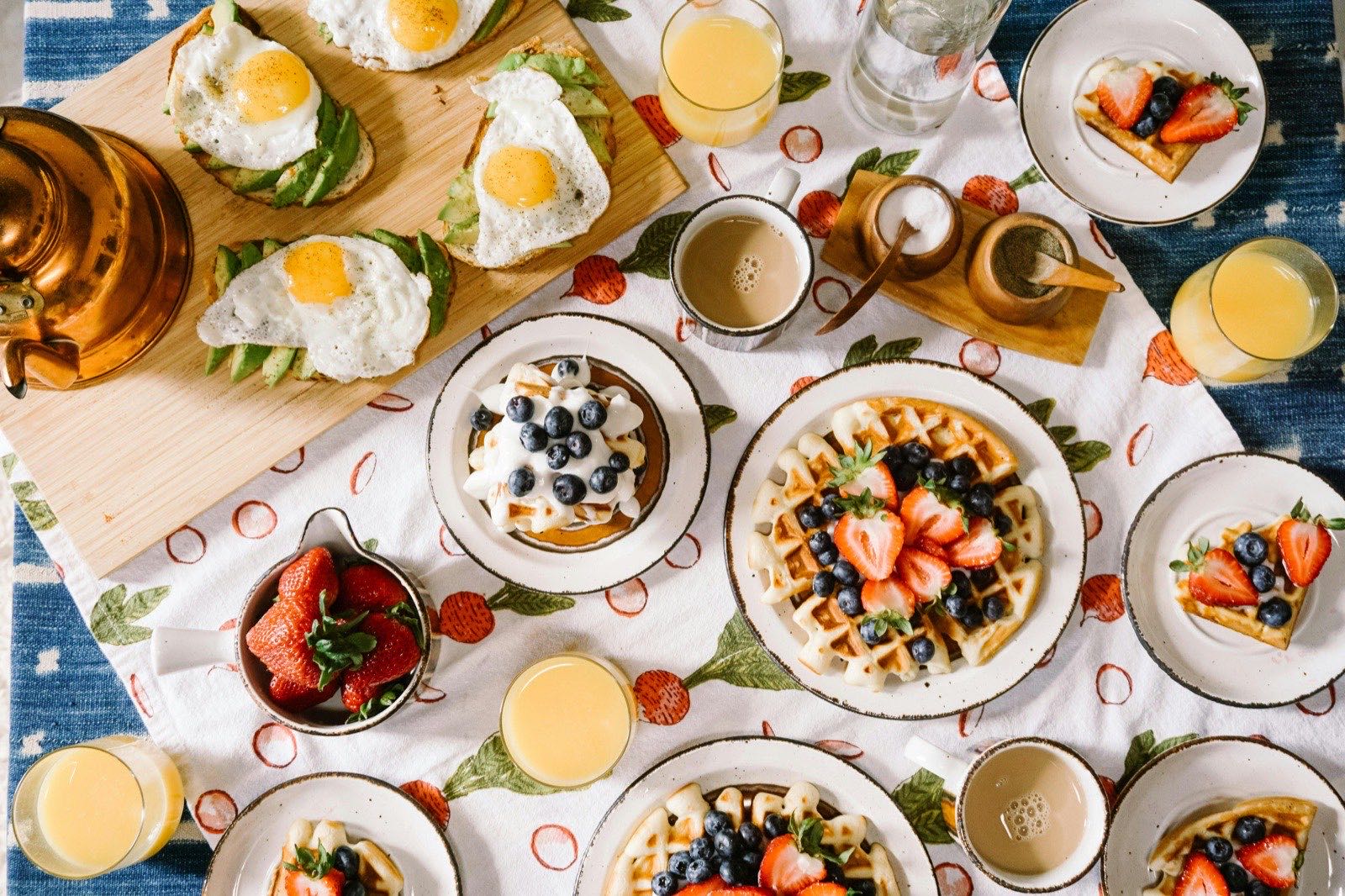 A brunch spread with waffles, eggs, and juice on a table