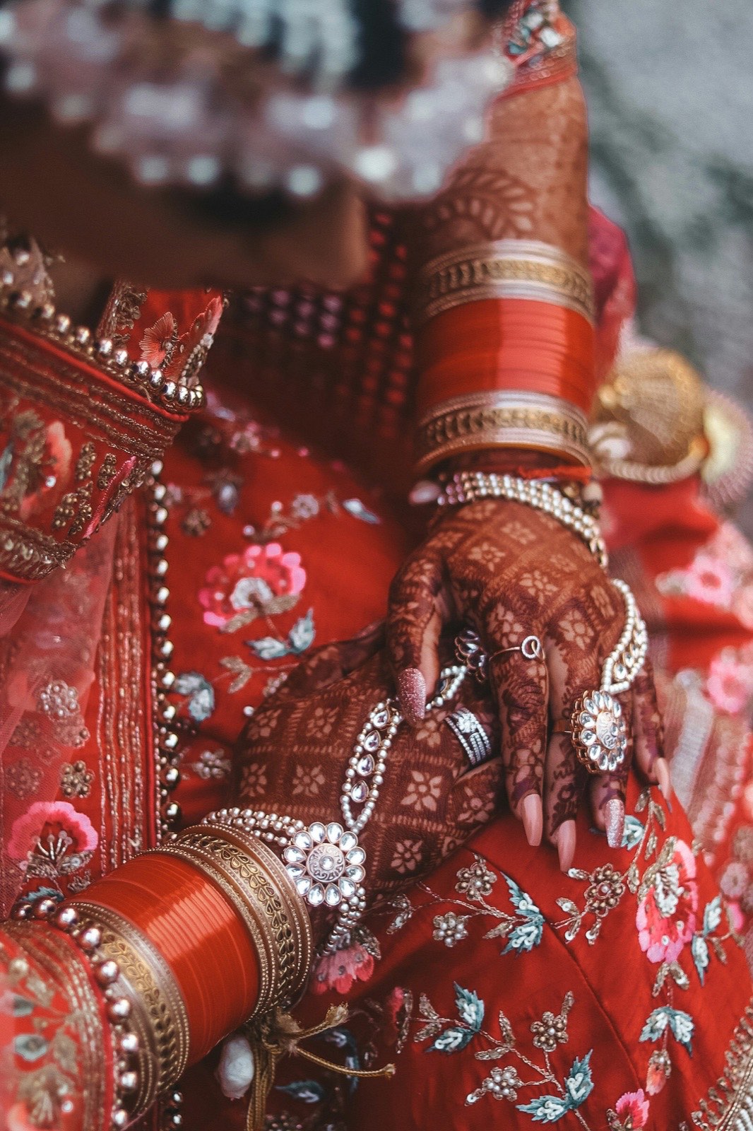 Hands covered in intricate henna with red and gold bangles