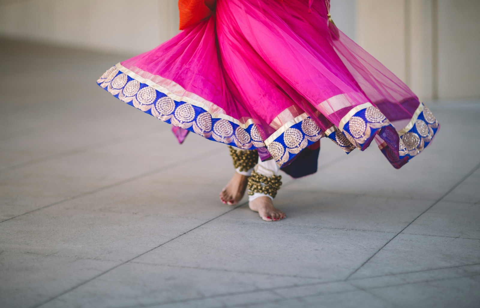 A dancer mid-twirl in a bright lehenga on the sangeet floor